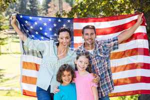 Happy family smiling with an american flag in a park