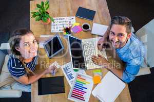 Smiling partners working at desk using laptop and tablet