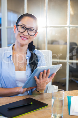 Smiling businesswoman sitting at her desk and working with table