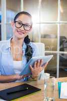 Smiling businesswoman sitting at her desk and working with table