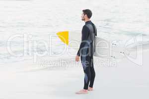 Man in wetsuit with a surfboard on a sunny day