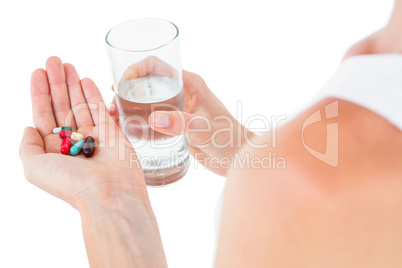 Woman holding batch of pills and glass of water