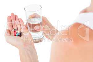 Woman holding batch of pills and glass of water