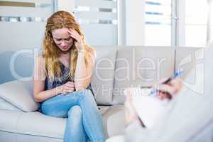 Psychologist talking with her depressed patient and taking notes