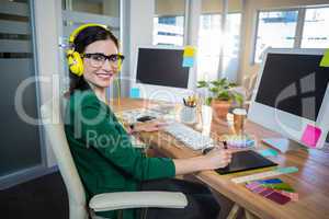 Smiling brunette working at her desk and listening music