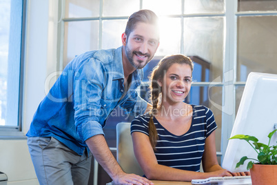 Smiling colleagues working together on computer