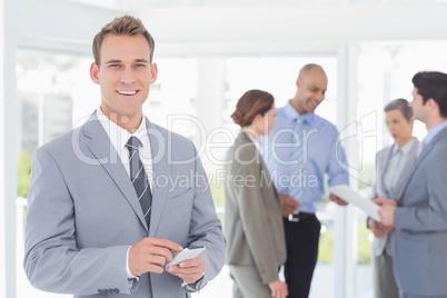 Businessman texting while his colleagues discussing