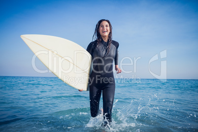 woman in wetsuit with a surfboard on a sunny day