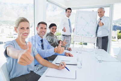 Business team smiling at camera showing thumbs up