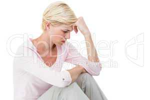 Depressed blonde woman sitting on the floor
