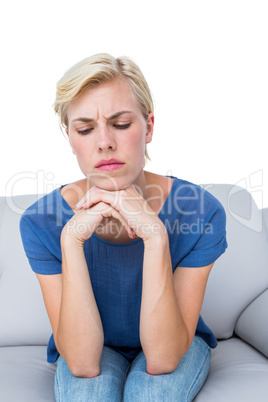 Thoughtful blonde woman sitting on the couch