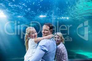 Happy family looking at camera behind a fish tank