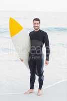 Man in wetsuit with a surfboard on a sunny day