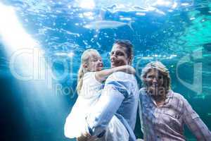 Happy family looking at camera behind a fish tank