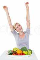 Happy blonde woman cheering while sitting above healthy food