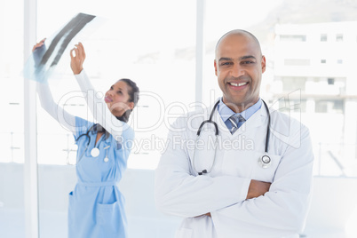 Smiling doctors looking at camera and analyzing xray Smiling doctors looking at camera and analyzing xray