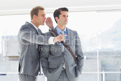 Businessman telling secret to his colleague