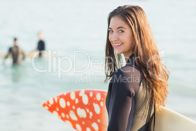 Group of friends on wetsuits with a surfboard on a sunny day