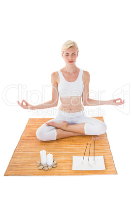 Fit woman meditating on bamboo mat