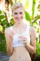 Happy blonde woman holding pill and glass of water