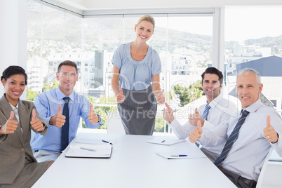 Business team smiling at camera showing thumbs up