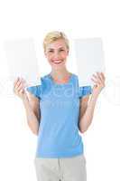 Happy blonde woman holding sheets of paper