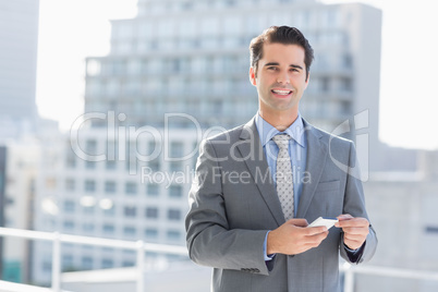 Smiling businessman texting with his mobile phone