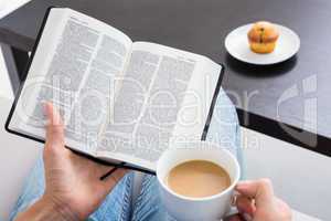 Woman reading a book and holding cup of coffee