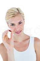 Smiling blonde woman holding red pill