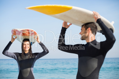 happy couple in wetsuits with surfboard on a sunny day