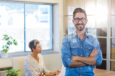 Smiling man standing arms crossed with his partner behind