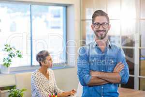 Smiling man standing arms crossed with his partner behind