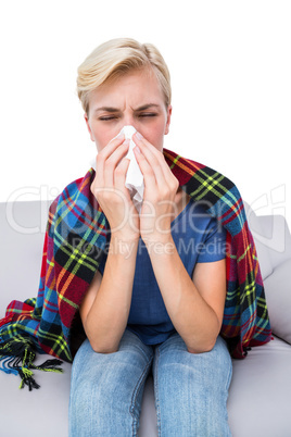 Sick blonde woman blowing her nose