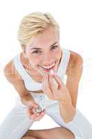 Smiling blonde woman holding pill and looking at camera