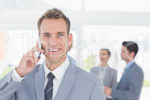 Businessman having phone call while his colleagues discussing