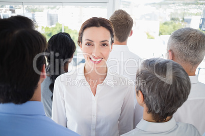 Smiling businesswoman with colleagues back to camera