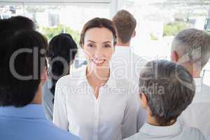 Smiling businesswoman with colleagues back to camera