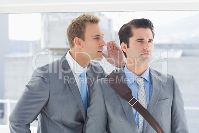 Businessman telling secret to his colleague