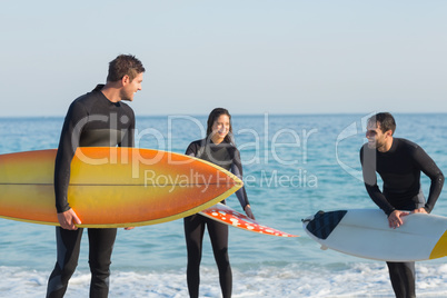 Group of friends on wetsuits with a surfboard on a sunny day