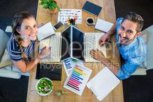 Smiling partners working at desk using laptop