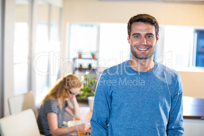 Smiling casual businessman posing with his partner behind