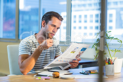 Casual businessman drinking coffee and reading magazine at his d