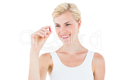 Smiling blonde woman looking at red pill