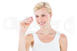 Smiling blonde woman looking at red pill