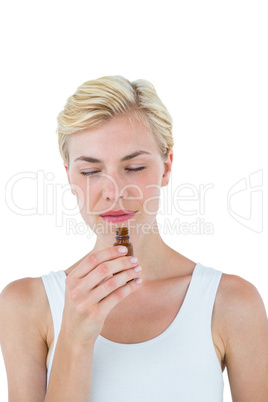 Gorgeous blonde woman smelling bottle of medicine