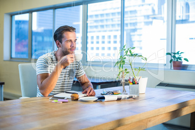 Casual businessman drinking coffee at his desk