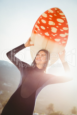 woman in wetsuit with a surfboard on a sunny day