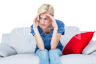 Thoughtful blonde woman sitting on the couch