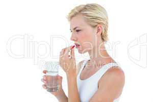 Pretty blonde woman holding glass of water and ready to swallow