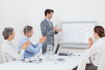 Business team applauding and looking at white screen